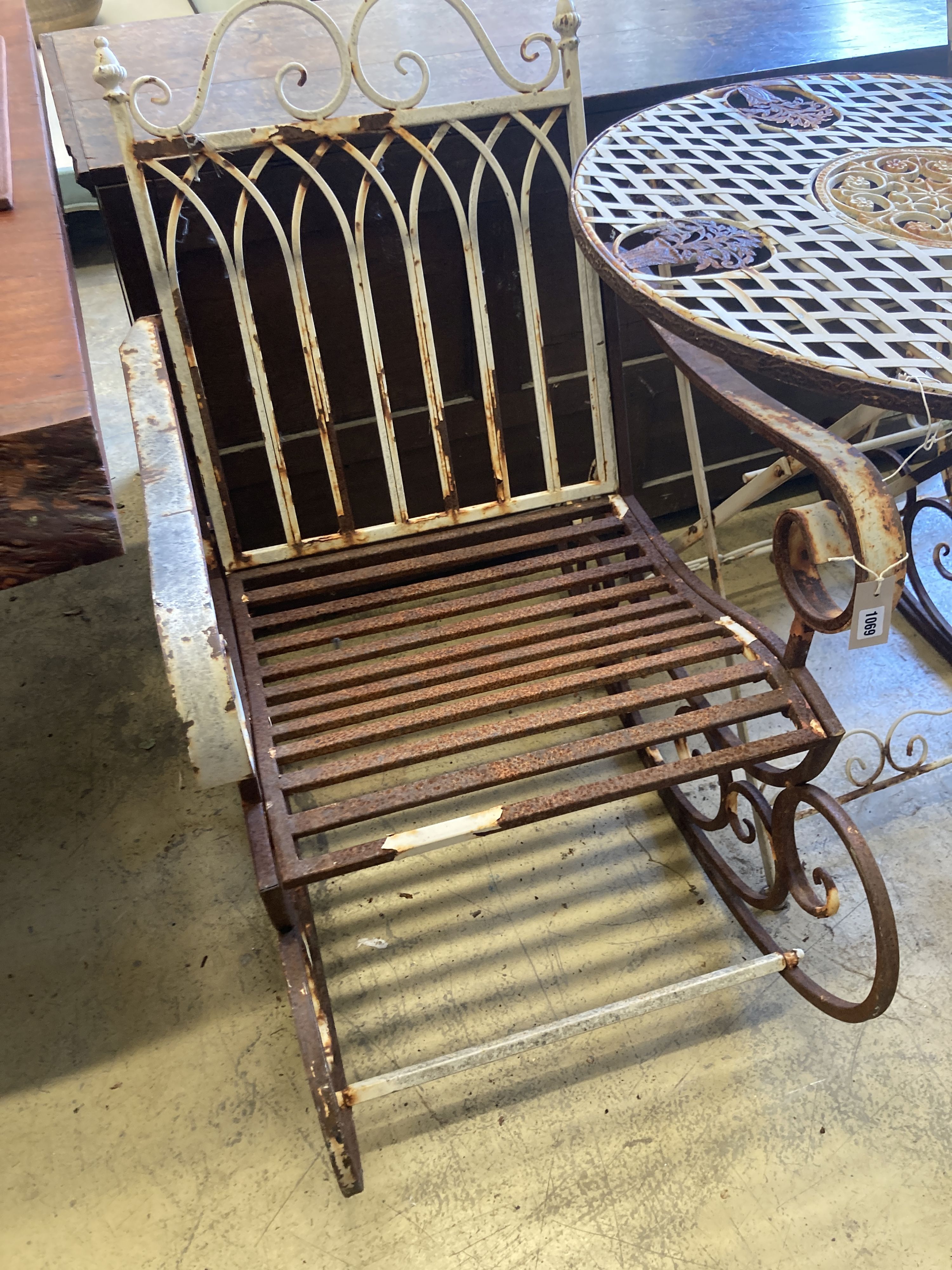 A pair of painted wrought iron garden rocking chairs together with a circular wrought iron folding garden table, diameter 71cm, height 76cm